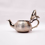 Side view of silver modern teapot showing curved spout