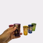 Hand holding colored Moroccan tea glass showing scale