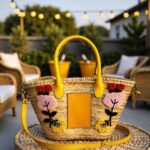 Yellow leather handle with contrast topstitching attached to handwoven straw crossbody bag
