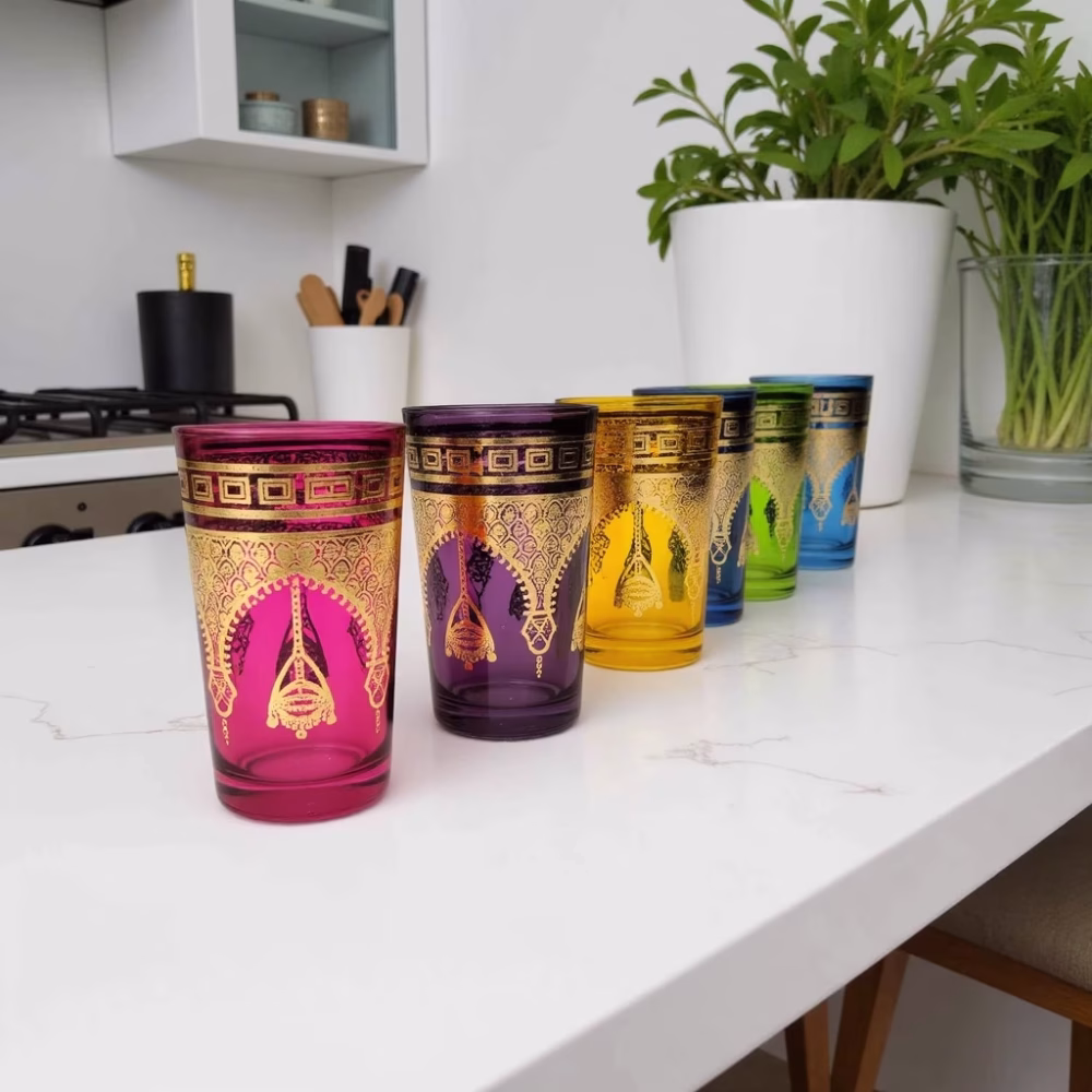 Set of six Moroccan colored tea glasses with gold henna design on white counter