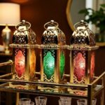 Close-up of engraved brass candle holder set showing blue and gold glass with intricate dome top and handle