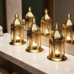 Five ornate engraved brass candle holders with hexagonal shape and filigree dome tops on white surface