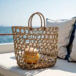 Straw mesh beach bag hanging on hook with open-weave knotted pattern in natural tan