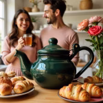 Green enameled teapot on table with fresh croissants and tea service