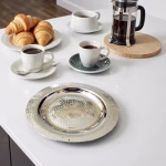Hand hammered silver decorative tray with breakfast setting and croissants on white countertop