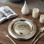 Hand hammered silver decorative tray with candle and magazine on wooden table