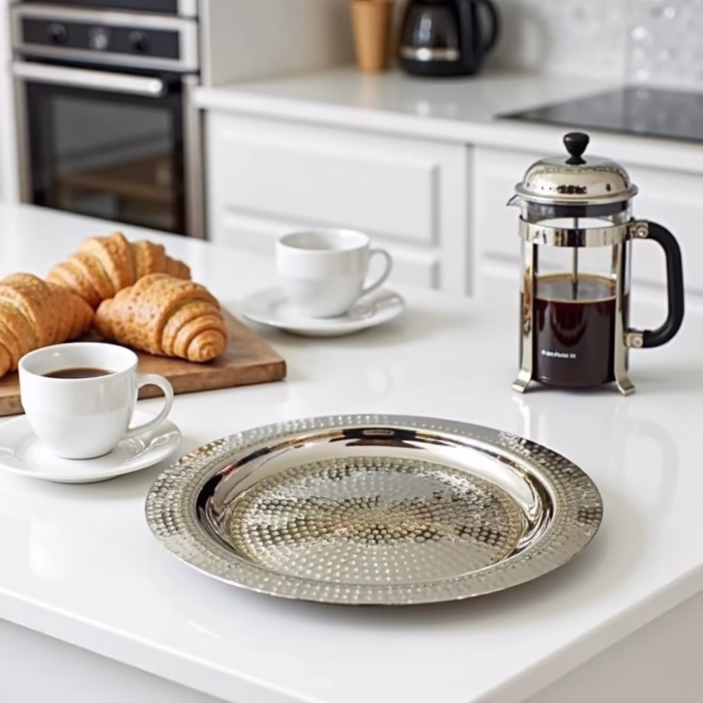 Silver hammered decorative tray with coffee cups and pastries on kitchen counter