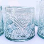 Close-up of hand-painted recycled glass with geometric henna pattern and dotted triangular design in turquoise