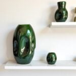 Contemporary ceramic vase green with organic form displayed on white floating shelves