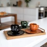 Set of handmade ceramic coffee cups in autumn colors with raised decorative patterns and matching saucers