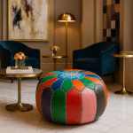 A vibrant leather pouf ottoman with multicolor patchwork design in a modern hotel lobby with teal chairs and gold accents.
