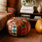 Cozy reading nook with a round leather pouf ottoman beside books, a floor lamp, and patterned cushions.