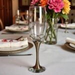 Silver champagne flutes with filigree metalwork stems and pearl accents on a decorated table