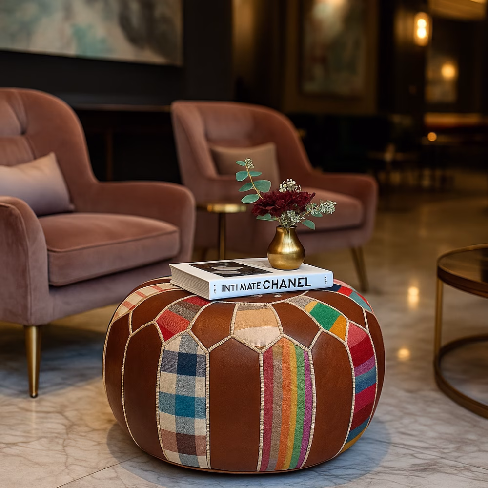 Luxurious interior featuring a round leather pouf ottoman used as a boho coffee table between velvet chairs.