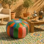 Handcrafted leather floor ottoman with rainbow patches on Moroccan tile patio near tea set and olive trees