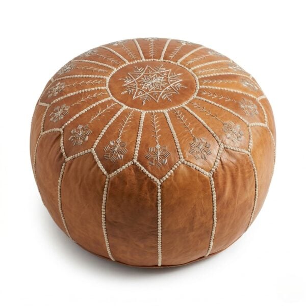 A tan leather floor ottoman showcasing detailed decorative stitching and a starburst pattern, isolated against a solid white background.