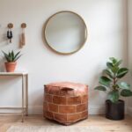 Handcrafted square leather floor pouf in modern entryway with round mirror, featuring cognac leather cube design