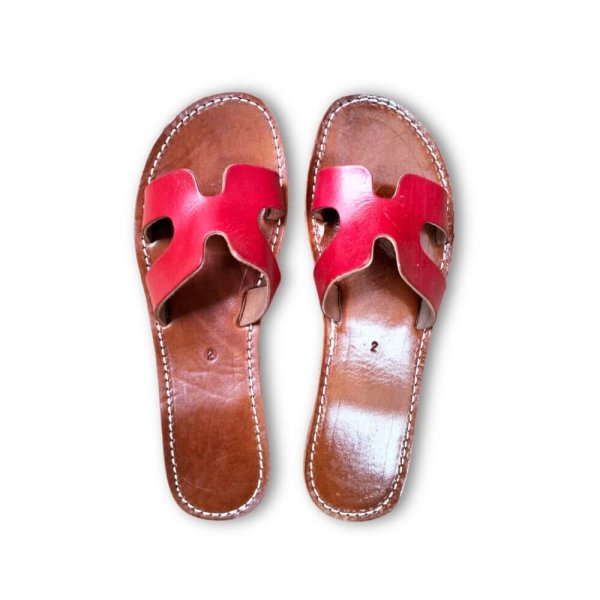 Vibrant pink leather flat sandals with interlocking H-strap and artisan hand-stitched brown footbed