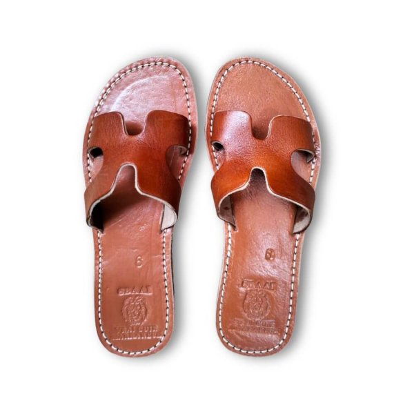 Brown leather flat sandals with H-strap design showing artisan craftsmanship and hand-stitched edges