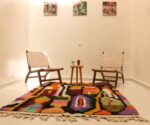 Pair of beige leather lounge chairs in gallery setting with colorful rug, mid-century style