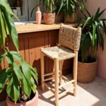 Artisanal handwoven bar chair featuring lemon wood frame and woven palm seat near white cabinets