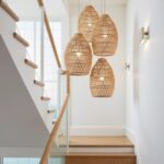 14" handwoven raffia lighting dome pendant casting shadow patterns on beige wall with round mirror
