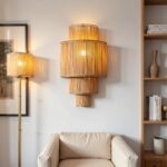 Natural raffia wall sconce with tiered vertical slats beside modern bookshelf and beige armchair setting