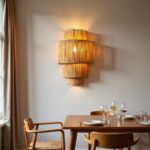 Handwoven raffia wall sconce with layered tiers illuminating dining room with warm bohemian ambiance