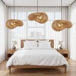 Three handwoven rattan pendant lamps arranged over bedroom with white bedding and natural wood furniture