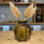 Handmade ceramic vase 30cm with raised patterns in amber brown glaze holding dried pampas grass on wooden table