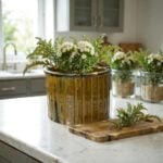 Artisan ceramic planter with reactive amber glaze and ridged texture holding wildflowers on white kitchen counter