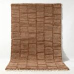 Handwoven Moroccan wool rug with textured grid pattern in natural brown tones and fringe detail
