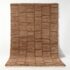 Handwoven Moroccan wool shag rug with geometric grid pattern in natural brown tones on white studio background
