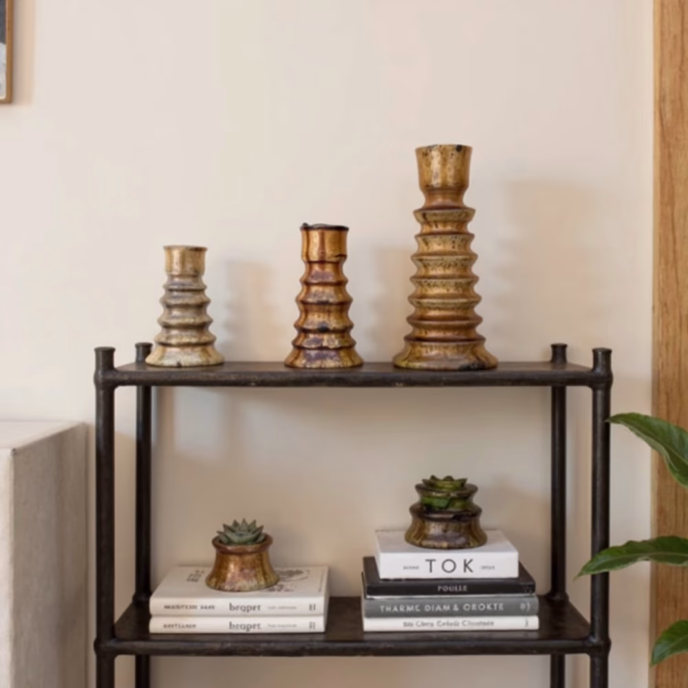 Brown stacked ring candleholder set on black metal shelf