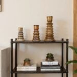 Graduated ceramic candleholders set with metallic gold finish on black shelf styled with books and succulents