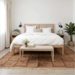 Handcrafted Moroccan wool rug in neutral brown under bed in serene Scandinavian-style bedroom