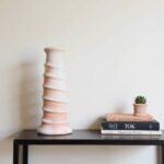 Handcrafted ceramic candle holder in white with spiral grooves, Tamegroute pottery on black shelf with books