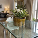 Ceramic plant pots displayed on glass table with greenery