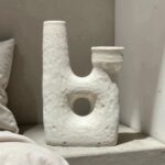 Artisan ceramic candle holders with textured white finish and circular cutout detail on neutral backdrop