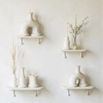 Handmade ceramic candleholder collection on white shelves featuring arch design and natural organic finish