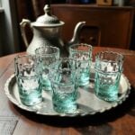 Aqua handblown diamond tea glasses on a hammered silver Moroccan tray next to a traditional brass teapot