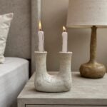U-shaped ceramic double candleholder with lit candles, showcasing textured speckled finish and artisan craftsmanship
