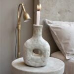 Handcrafted ceramic candle holder in weathered gray finish, sculptural bottle shape with side cutout detail