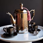 Hammered silver-plated coffee server with black cups on tray