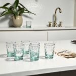 Recycled aqua handblown diamond tea glasses on a stone counter near Moroccan brass fixtures and a towel