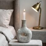 Gray pottery ceramic candle holder on bedside table with brass lamp, Scandinavian minimal decor