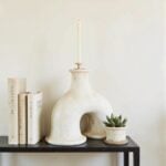 White ceramic candleholder with arch detail styled with books and succulent on modern black console table