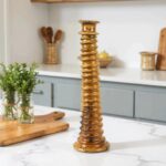 Glossy brown ceramic candle holder with architectural ridged design on marble kitchen counter