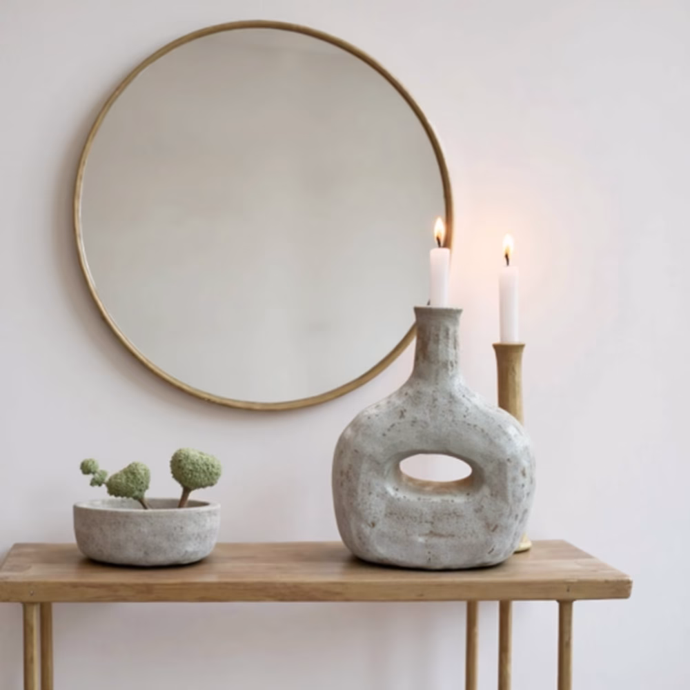 Minimalist gray bottle candleholder on wooden table with round mirror