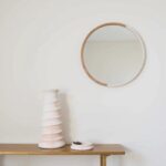 Sculptural ceramic candle holder, white spiral tower displayed on wood shelf beneath round mirror